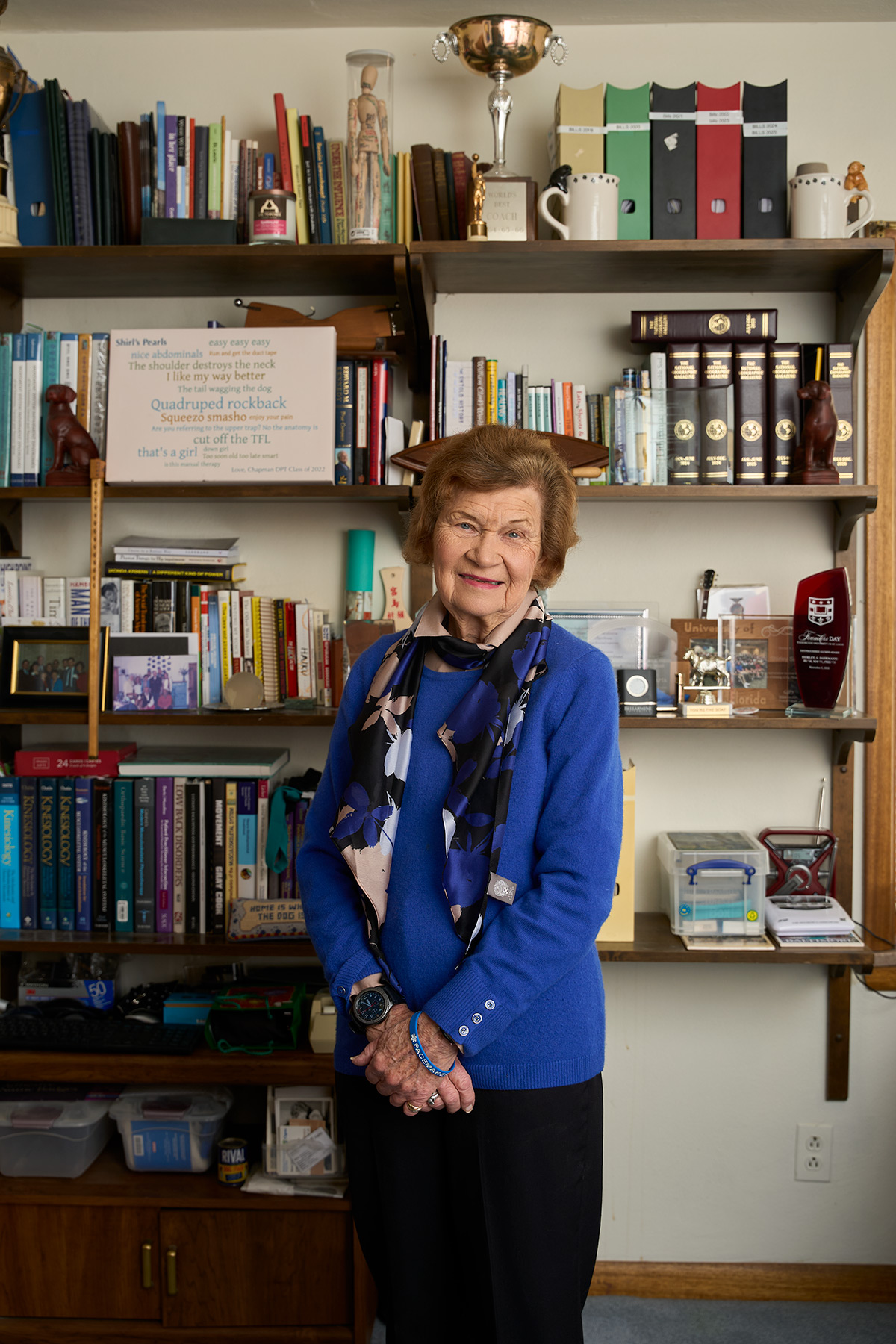 Shirley Sahrmann standing in front of her bookcase
